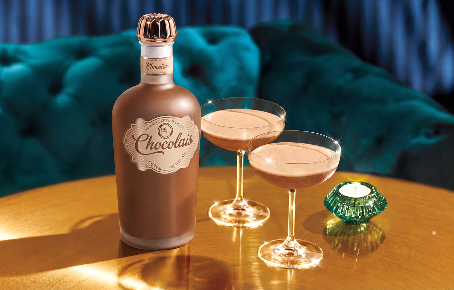 Chocolais bottle with two filled cocktail glasses on a golden table